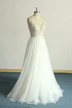 a white wedding dress on a mannequin in front of a blue carpeted floor