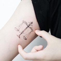 a woman's arm with a tattoo on it that has an image of a hammer and scale