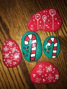 some rocks decorated with candy canes and snowflakes on a wooden table top