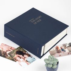 an open book sitting on top of a table next to photos and a potted plant