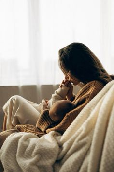 a woman sitting on a couch holding a baby