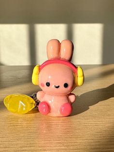 a little toy sitting on top of a wooden table next to a yellow bowl and spoon