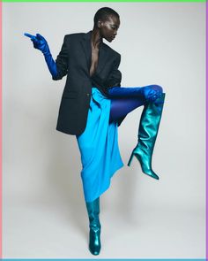 a woman in blue tights and boots posing with her legs spread out to the side