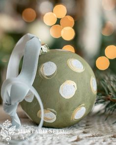 a green ornament with white polka dots on it and a ribbon around the neck