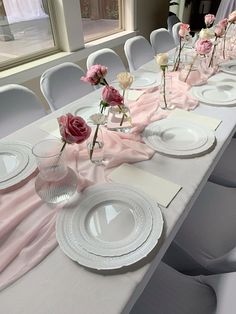 the table is set with white plates and pink napkins