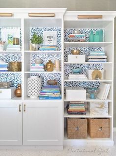 a white bookcase with blue and white wallpaper on it's sides is shown