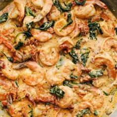 a pan filled with shrimp and spinach on top of a stove