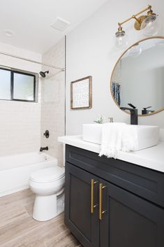 a white toilet sitting next to a bath tub in a bathroom on top of a hard wood floor