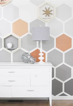 a white dresser sitting in front of a wall with hexagonal tiles on it