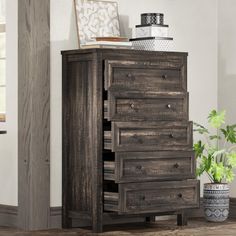 a tall wooden dresser with drawers next to a potted plant