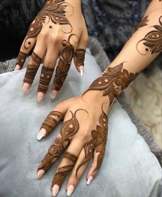 two hands with henna tattoos on them, one is brown and the other is white