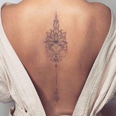 the back of a woman's neck with a lotus tattoo on her lower back