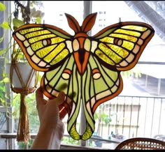 a stained glass butterfly hanging from a ceiling in a room filled with potted plants