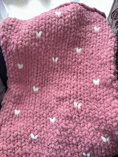 a pink crocheted blanket with white butterflies on it sitting on top of a chair