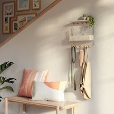 a wooden bench sitting under a stair case next to a wall mounted shelf filled with plants