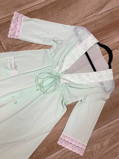 "Here we have fabulous vintage Shadowline dressing gown from the 1970s. Made up of 100% soft and stretchy nylon, this gown features a full button up front with fabric covered buttons. Adorable lace trimmed pocket on one side. Drawstring tie waist allows for a more tailored look. Snap closure underneath top button. Lovely light mint green color. There is a small very faint discoloration at the midriff area between the buttons, I was unable to get it out with washing it. Price has been adjusted to Vintage Fitted Long Sleeve Nightgown, Fitted Long Sleeve Vintage Nightgown, Vintage Long Fitted Robe, Fitted Long Sleeve Robe With Lace Trim, Fitted Robe With Lace Trim And Long Sleeves, Fitted Vintage Robe For Daywear, Fitted Lace Trim Robe For Spring, Long Gown Dress, Mint Green Color