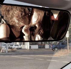 two women kissing in the rear view mirror of a car