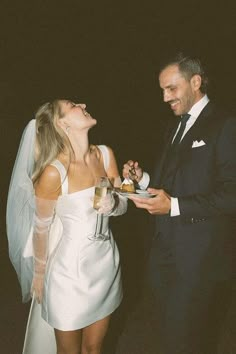 a man in a tuxedo standing next to a woman in a white dress