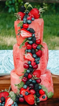 a watermelon cake with berries and strawberries on top is sitting on a table