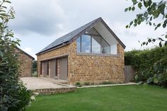 a brick house with a sloping roof and large windows on the side of it's building