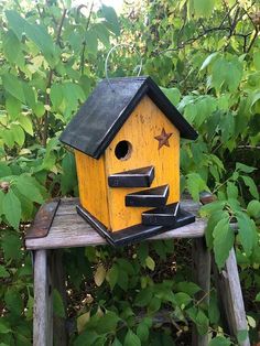 a yellow birdhouse sitting on top of a wooden bench