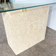 a table with a glass top sitting on carpeted floor next to a white wall