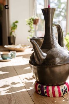 a large metal vase sitting on top of a wooden table