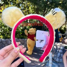 someone is holding up a mickey mouse ears headband that has been made to look like winnie the pooh