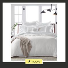 a bed with white sheets and pillows in a room next to windows that reads macy's