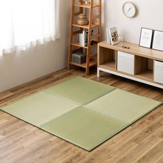 a living room with wooden flooring and white walls in the corner, along with a green rug that has squares on it