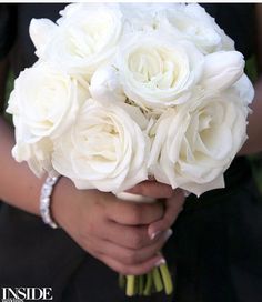 a woman holding a bouquet of white roses