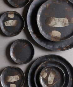 an assortment of black and gold plates on a white counter top with brown stains all over them