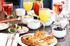 a table topped with waffles, fruit and drinks