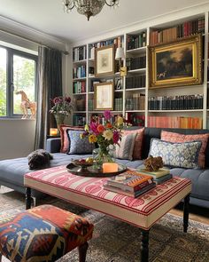 a living room filled with lots of furniture and bookshelves next to a window