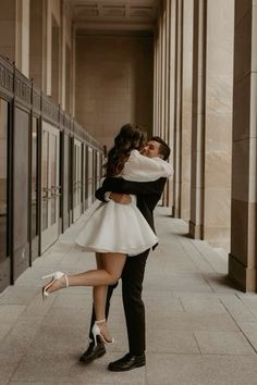 a man and woman are kissing in an empty hallway with their arms around each other