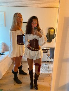 two women dressed in costume taking a selfie with their cell phone while standing next to each other