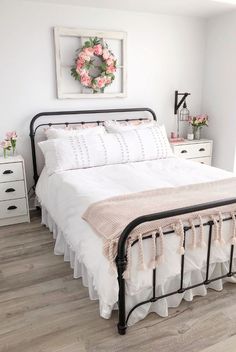 a white bed with pink flowers on the headboard and foot board next to it