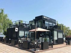 an outdoor dining area with tables and umbrellas in front of a building on the water