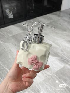 a hand holding a soap dispenser with a pink bow on it