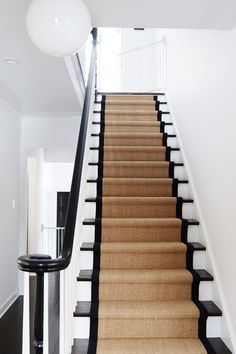 a staircase with black railing and beige carpet