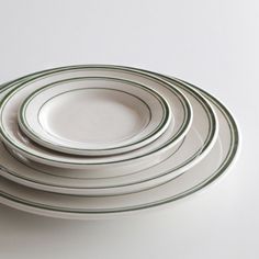 a stack of white and green plates stacked on top of each other in front of a white background