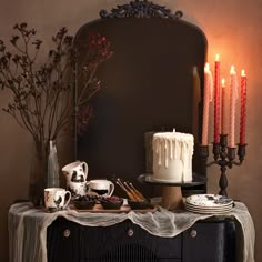 a table topped with a cake next to candles and other decorating items in front of a mirror