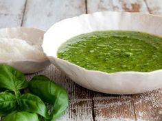 a white bowl filled with green soup next to some bread