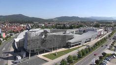 an aerial view of a large building in the middle of a town with mountains in the background