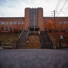 an old brick building with stairs leading up to the top and bottom floors, on a cloudy day