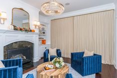 a living room filled with furniture and a fire place in front of a window covered in curtains