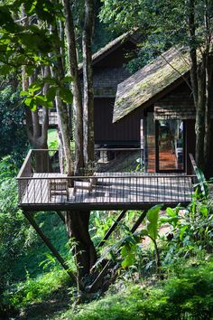 a tree house in the woods with a deck and stairs leading up to it's roof