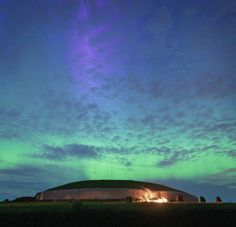 the aurora lights shine brightly in the night sky over an old building and grassy field