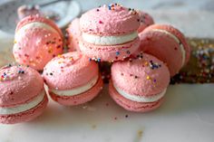 pink macaroons with white frosting and sprinkles are stacked on top of each other