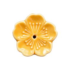 a yellow flower shaped dish on a white background